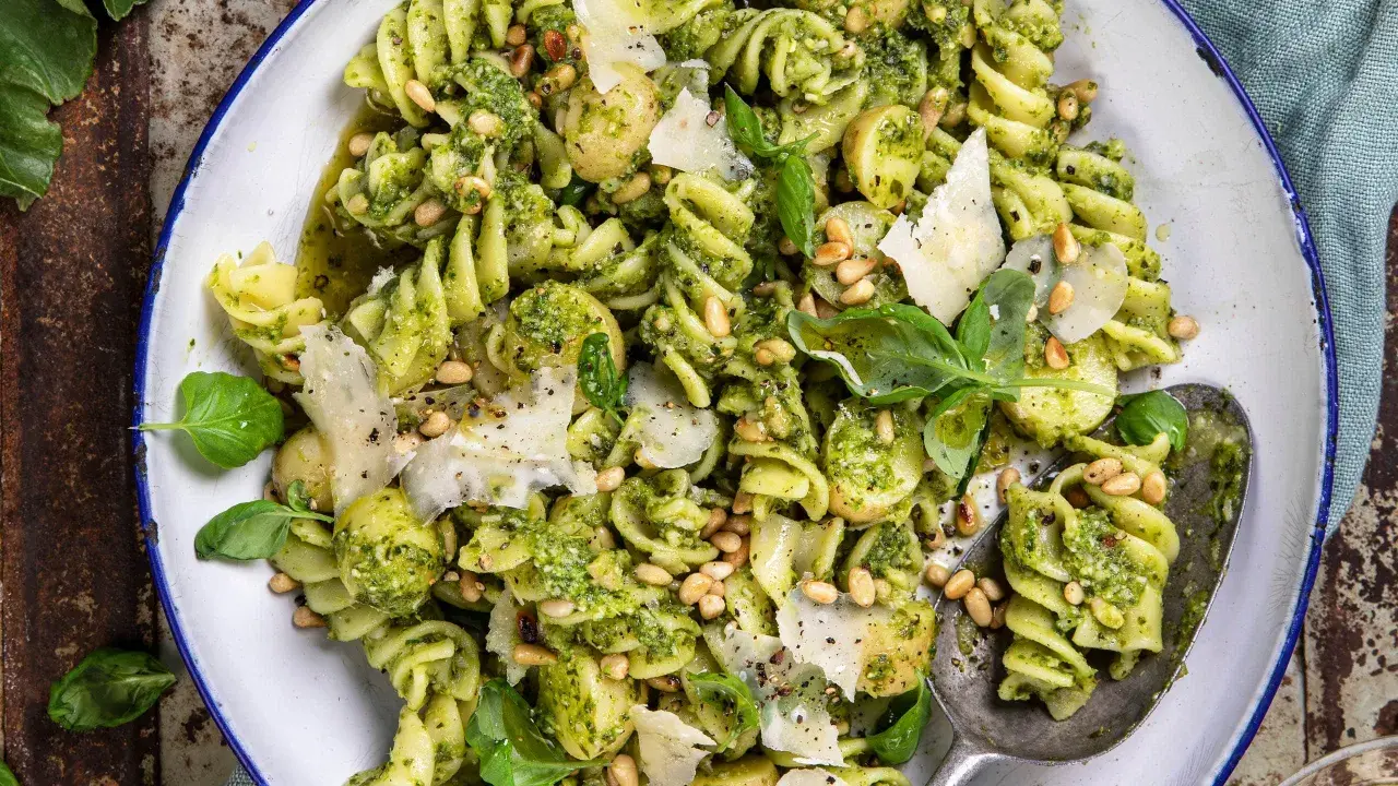 En närbild av en härlig pastasallad med pesto, pinjenötter, parmesan och färsk basilika. Perfekt för en lätt lunch.