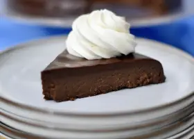 En bit fransk chokladtårta med en virvel av vispad grädde på en tallrik.
