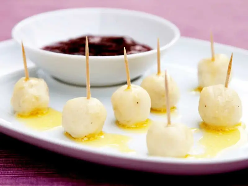Små, gyllene kroppkakor med tandpetare, serverade med en skål mörk sylt. Ett spännande recept att prova!
